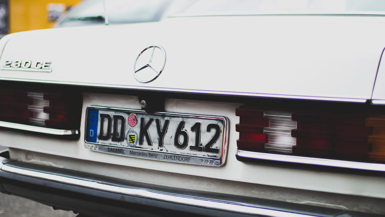 The rear of a classic Mercedes-Benz sedan at the kerb, its license plate and tail lights in view
