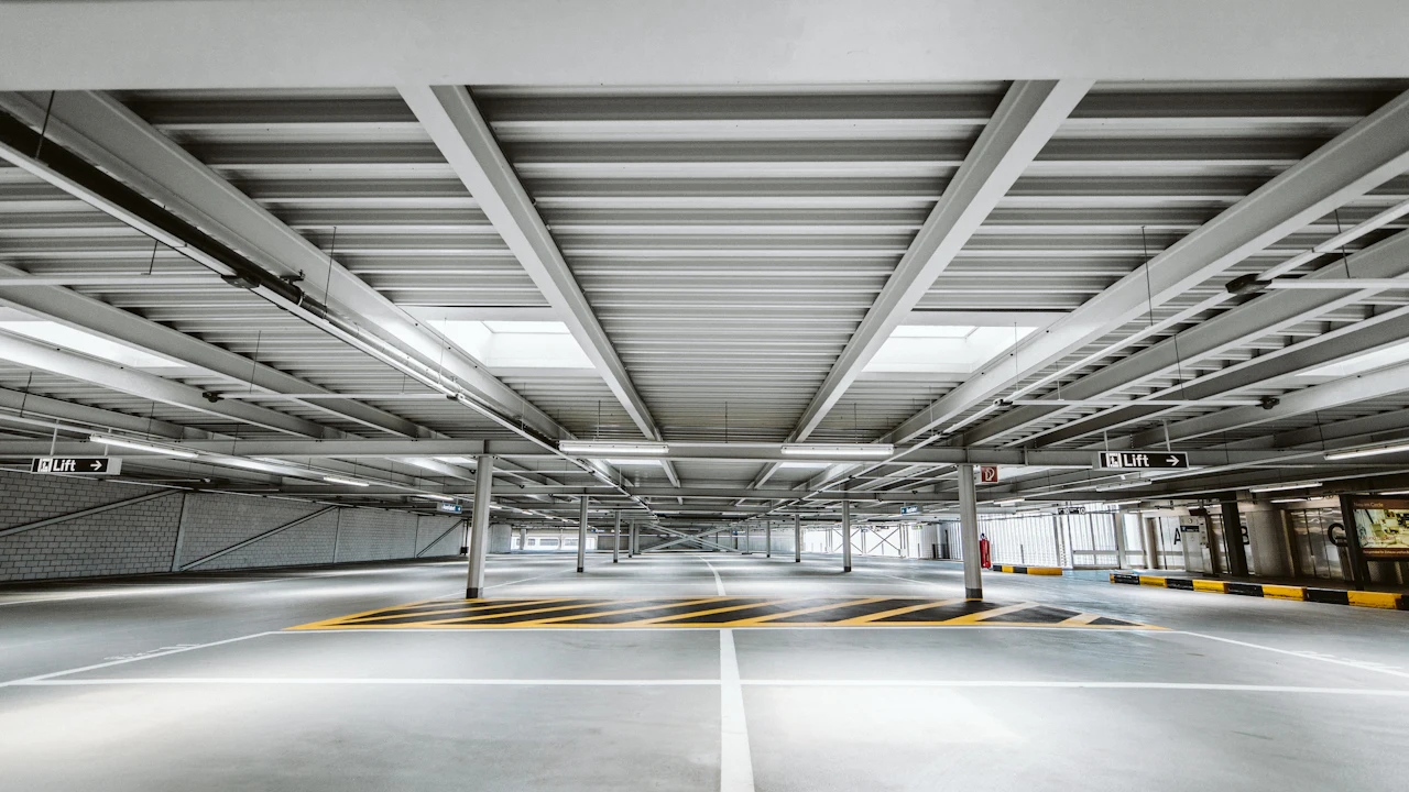An empty multi-storey car park deck, bays marked out under strip lighting