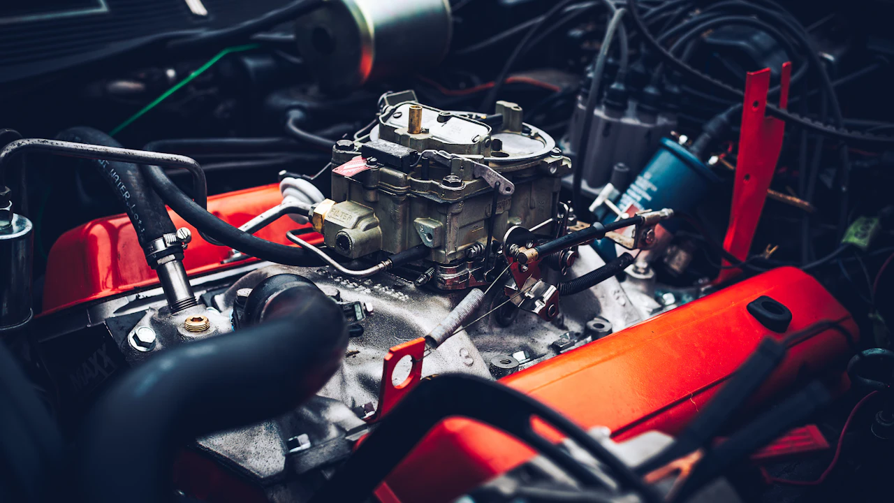 A close-up of an engine bay with the bonnet raised, hoses and the top of the engine block visible