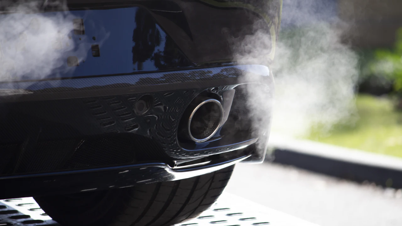 A car exhaust tailpipe photographed from behind with vapour drifting from it
