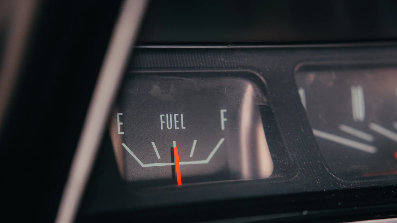 A fuel gauge needle sitting near empty on an older instrument panel