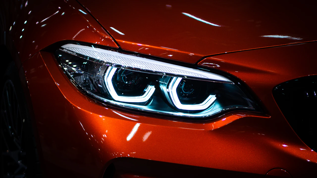 A modern LED headlight set into the orange bodywork of a coupe