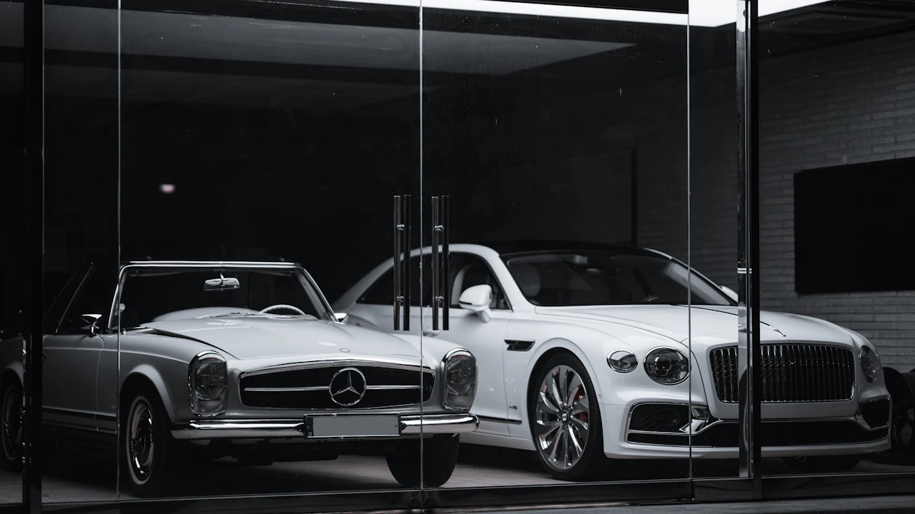 A vintage Mercedes-Benz and a modern Bentley parked behind a glass storefront