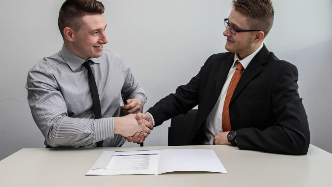 Two people shaking hands over a completed car sale