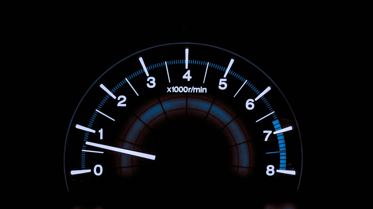 A rev counter dial glowing against a dark instrument panel