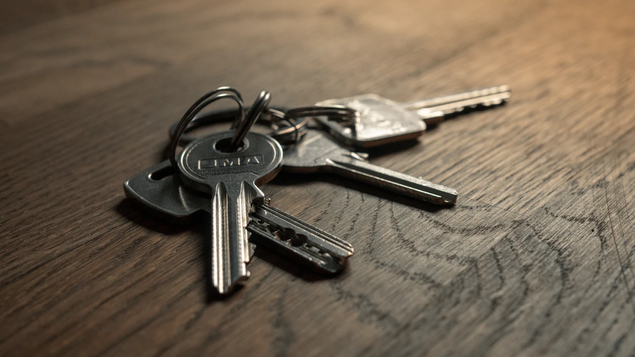 A set of car keys lying on a wooden table beside a folded document