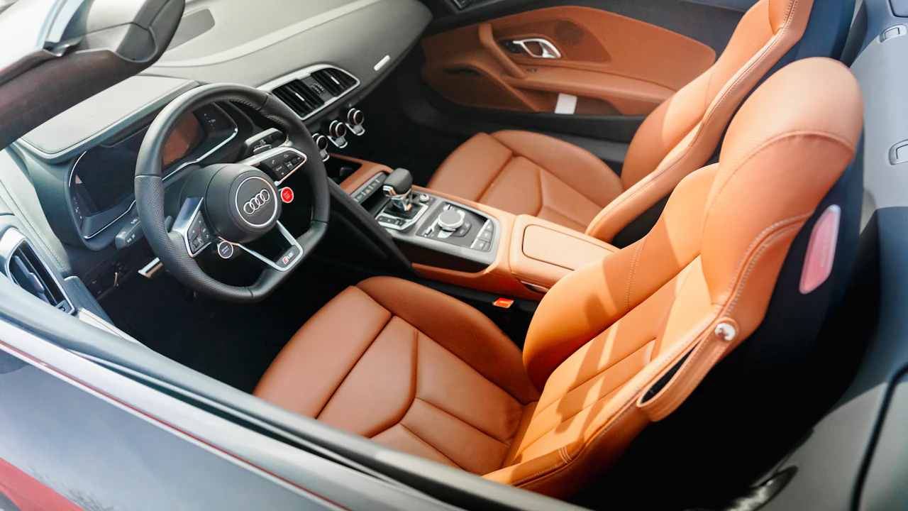 The interior of a car photographed from the rear seats, leather upholstery and the dashboard beyond